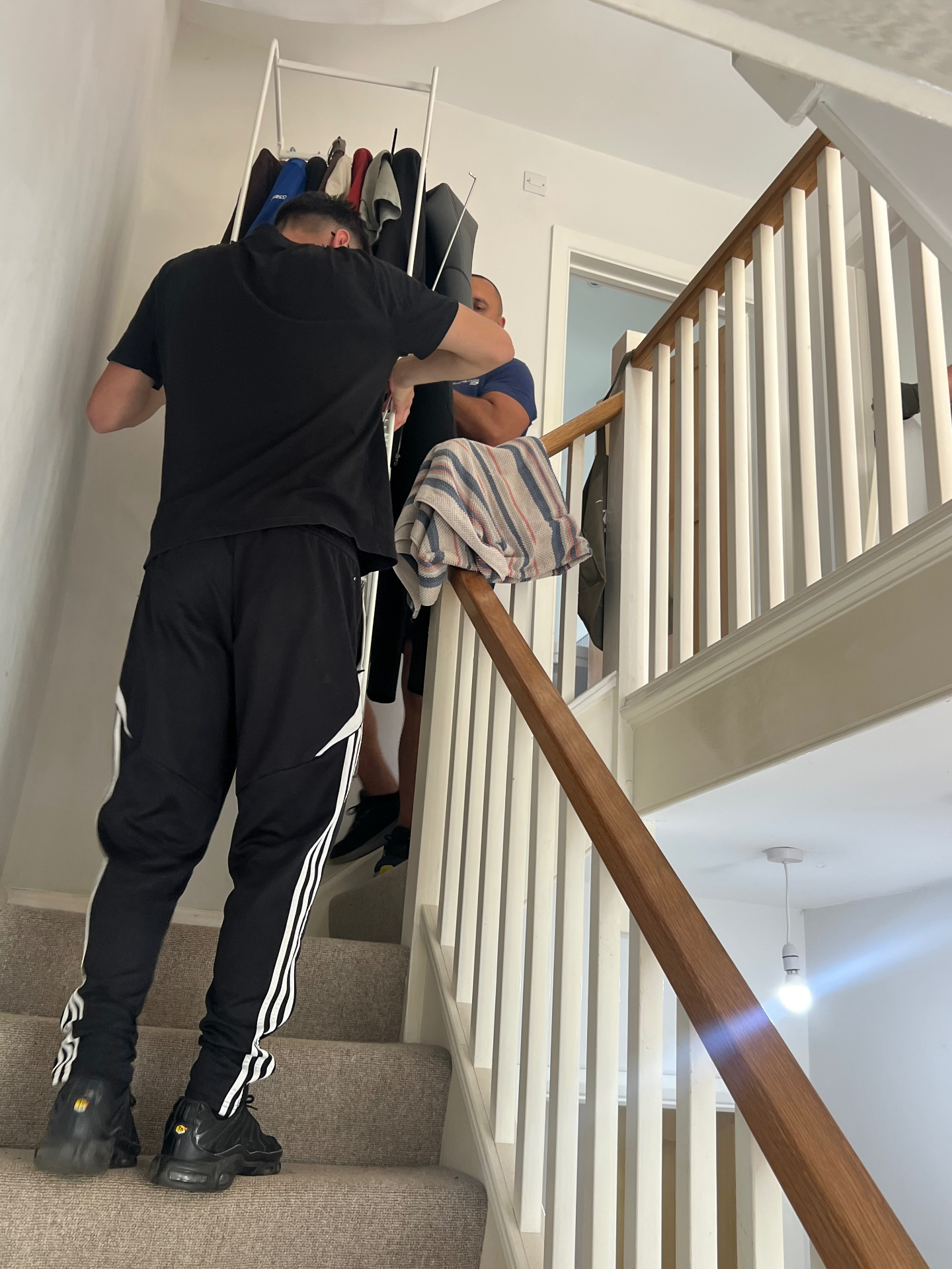 Professional movers carrying furniture up a flight of stairs in a UK home